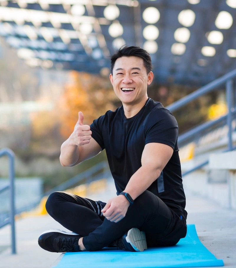 Foto seorang pria sedang duduk bersila sambil mengacungkan jempol